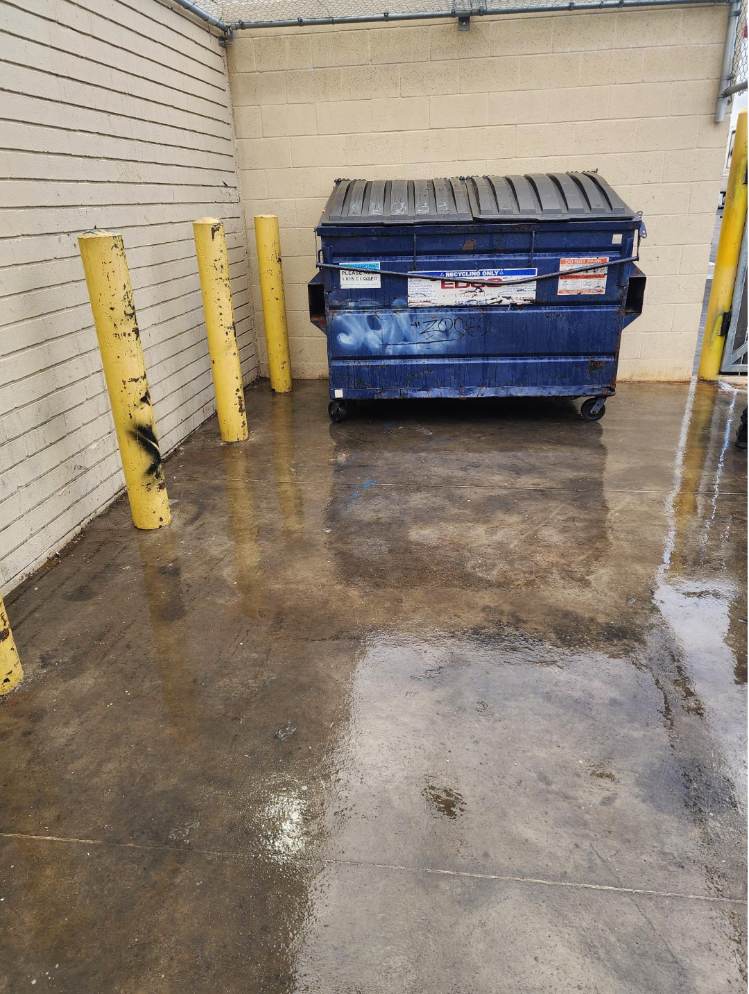 Clean pavement beside a dumpster