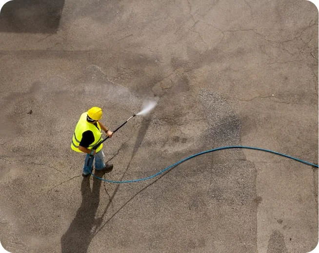 Worker pressure washing pavement